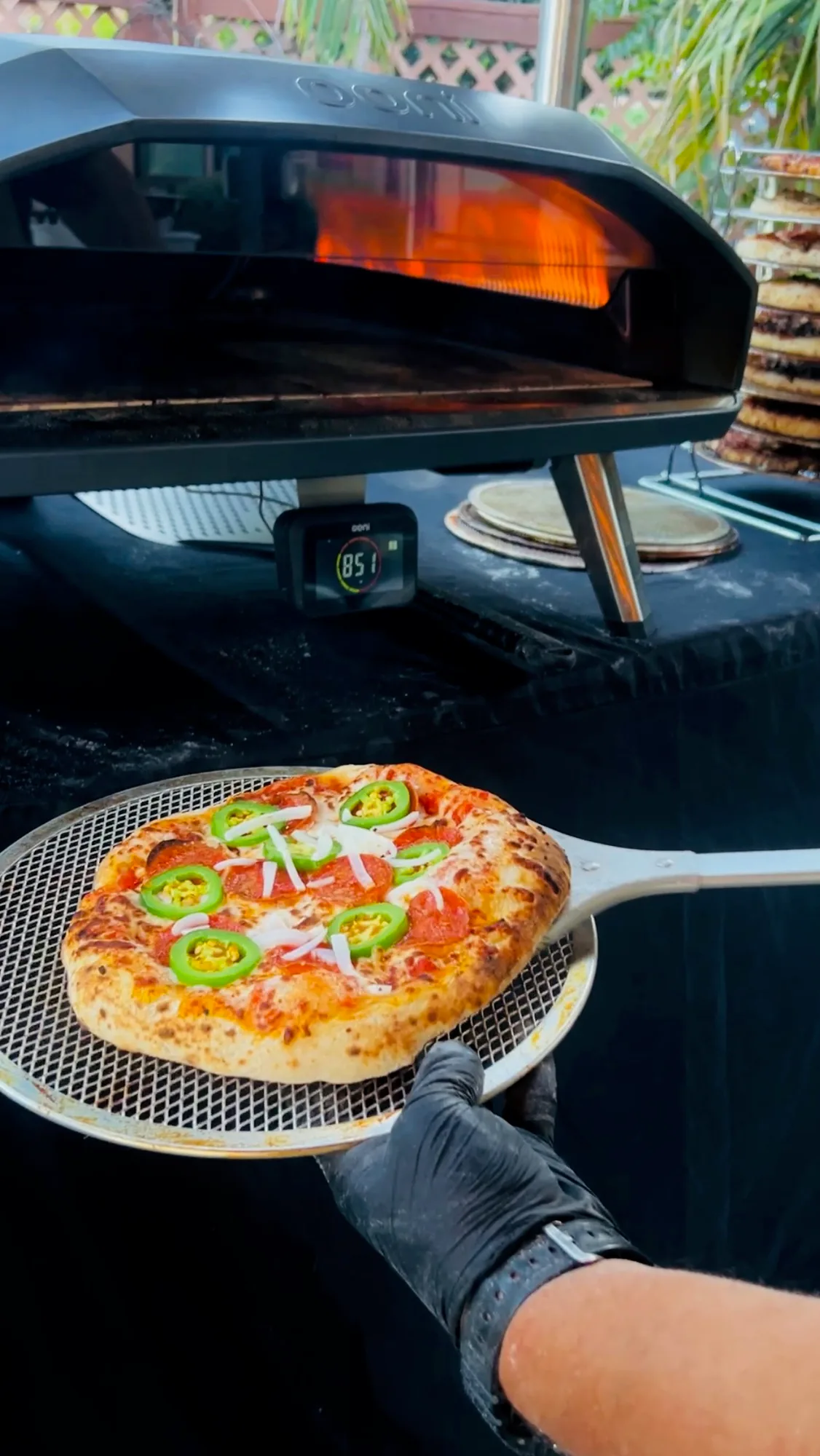 A finished pizza on the peel beside the oven at full heat.